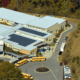 Aerial view of a high school in Pennsylvania with rooftop solar panels installed by Canopy Solar, surrounded by sports fields, school buses, and green landscaping on a sunny day